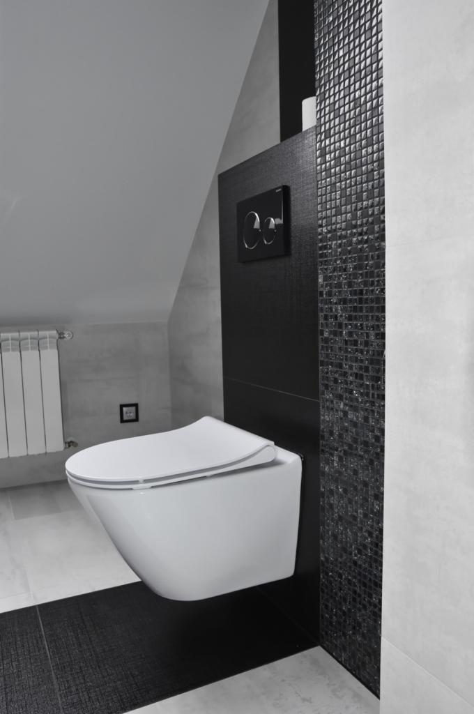 Nowoczesna, podwieszana toaleta w minimalistycznej łazience z czarno-białą mozaiką i matową czarną zabudową stelaża.