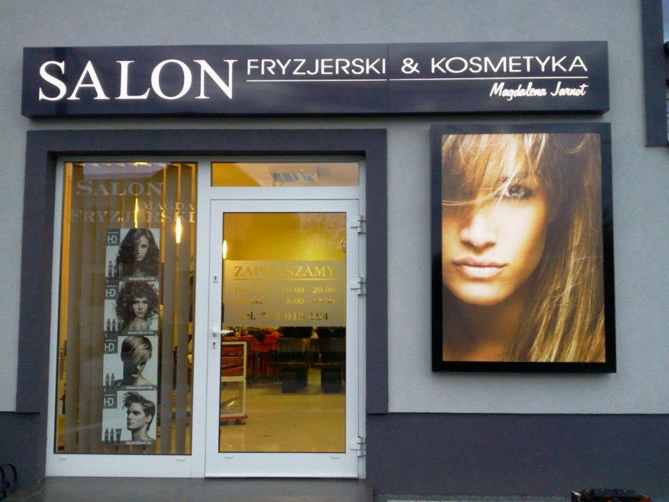 Fasada salonu fryzjerskiego z szyldem 'SALON FRYZJERSKI & KOSMETYKA' i plakatem z portretem kobiety z blond włosami
