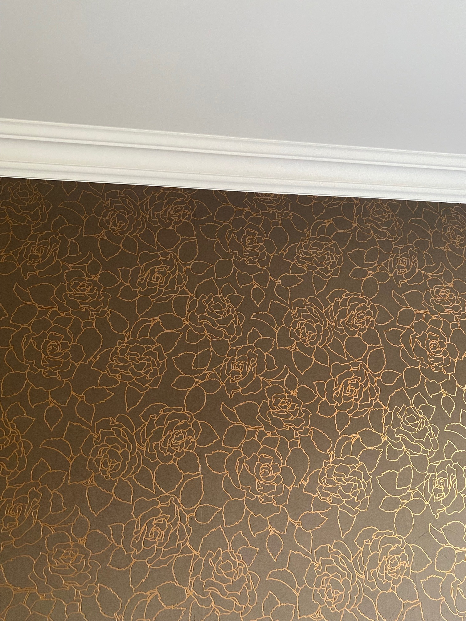 Brązowa ściana z motywem róż w kolorze złota, wykończona białym gzymsem sufitowym, wykonana w domu w Markach.