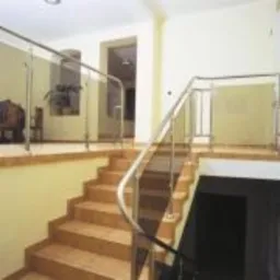 Schody wyłożone płytkami ceramicznymi z balustradą ze stali nierdzewnej i szkła, widok z dołu, jasne wnętrze.