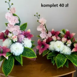 Dwa stroiki kwiatowe z liliami, różami i chryzantemami w odcieniach różu, fioletu i bieli, umieszczone na drewnianym stoliku, z napisem 'komplet 40 zł' w prawym górnym rogu.