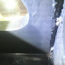 QNDT Adam Mękwiński - Szczegółowe ujęcie spawu łączącego elementy konstrukcji stalowej, widoczne niedoskonałości i odpryski farby.