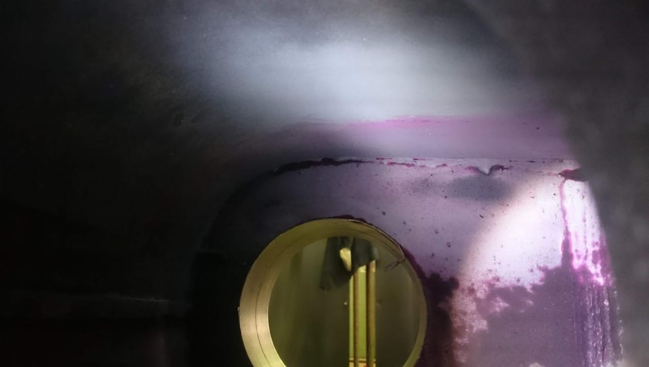 Wnętrze konstrukcji stalowej z widocznym otworem inspekcyjnym i śladami testu szczelności barwnikiem penetracyjnym.