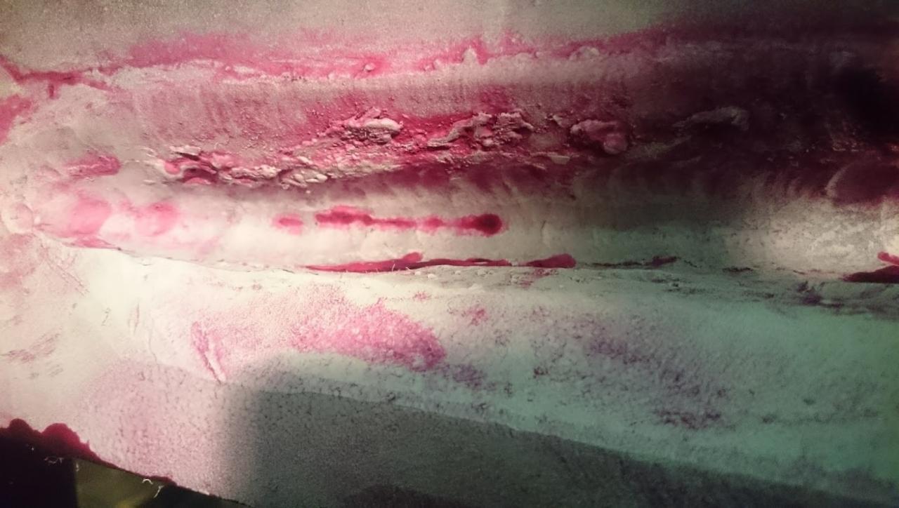 Wynik badania penetracyjnego spoiny stalowej z widocznymi wskazaniami w kolorze różowym.