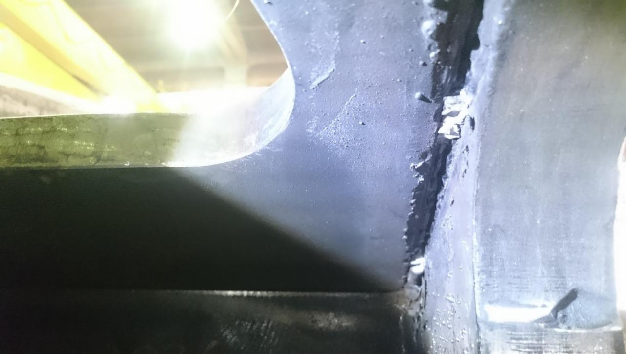 Szczegółowe ujęcie spawu łączącego elementy konstrukcji stalowej, widoczne niedoskonałości i odpryski farby.