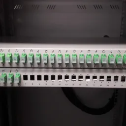 Panel krosowniczy światłowodowy z oznaczonymi portami A i B oraz numeracją od 1 do 24, zamontowany w szafie rack.