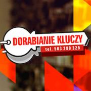 Grafika reklamowa: biały klucz z czerwonym napisem 'DORABIANIE KLUCZY' i numerem telefonu na czerwonym tle, abstrakcyjne kolorowe tło.