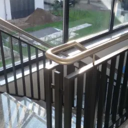 Wewnętrzne schody z szarymi, metalowymi barierkami i nierdzewną poręczą w Rzeczenicy, widok z góry na marmurowe stopnie.