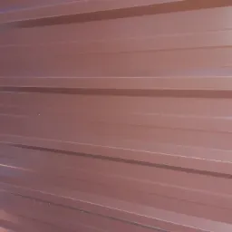 Ciemnobrązowa blacha trapezowa ułożona poziomo, widoczne regularne przetłoczenia i połyskliwa powierzchnia.