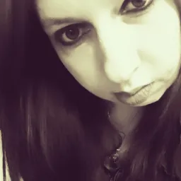 Portret kobiety z ciemnymi włosami, patrzącej w dół z intensywnym spojrzeniem, w sepii.