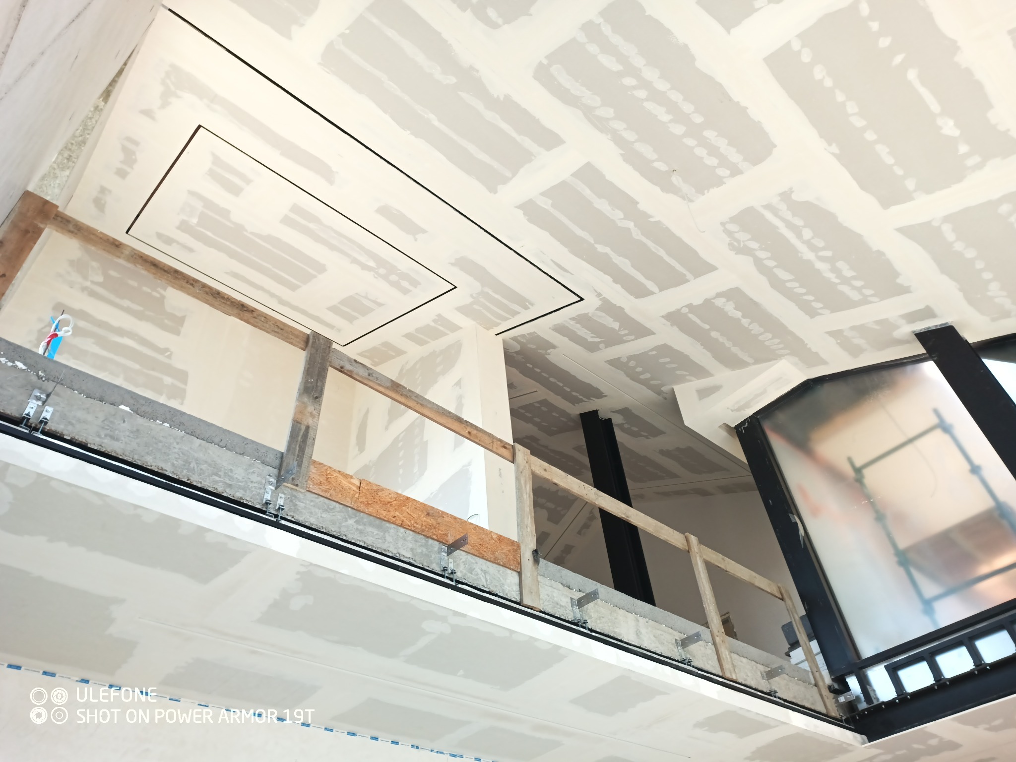 Sufit z zamontowanymi płytami, częściowo wyszpachlowany, z widoczną konstrukcją nośną i elementami instalacji.