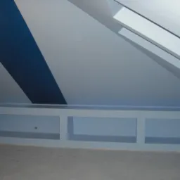 Pokój na poddaszu z ukośnym sufitem i oknem dachowym, pomalowany w biało-granatowe pasy, z wnękami w ścianie pod sufitem i surową posadzką.