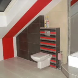 Wykończona łazienka na poddaszu z czerwonymi akcentami na ścianach i obudowie toalety, widoczne silikony budowlane na obudowie, biała umywalka i toaleta.