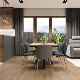 Wnętrze jadalni z drewnianym stołem, krzesłami z złotymi nogami, szarą sofą narożną i dużym oknem z widokiem na zieleń, dopełnione nowoczesnym oświetleniem i dekoracjami ściennymi.