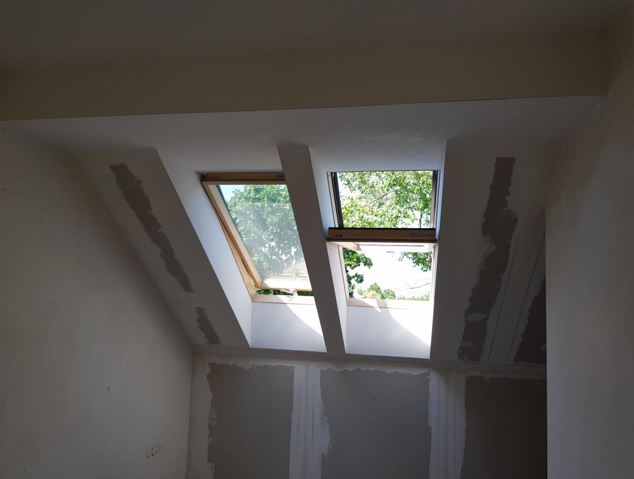 Poddasze ze świeżo osadzonymi oknami dachowymi, ślady po łataniu ścian gipsem, przygotowanie do dalszych prac wykończeniowych.