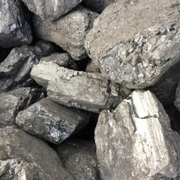 Kupa antracytu z widocznymi błyszczącymi powierzchniami i szarym pyłem węglowym.