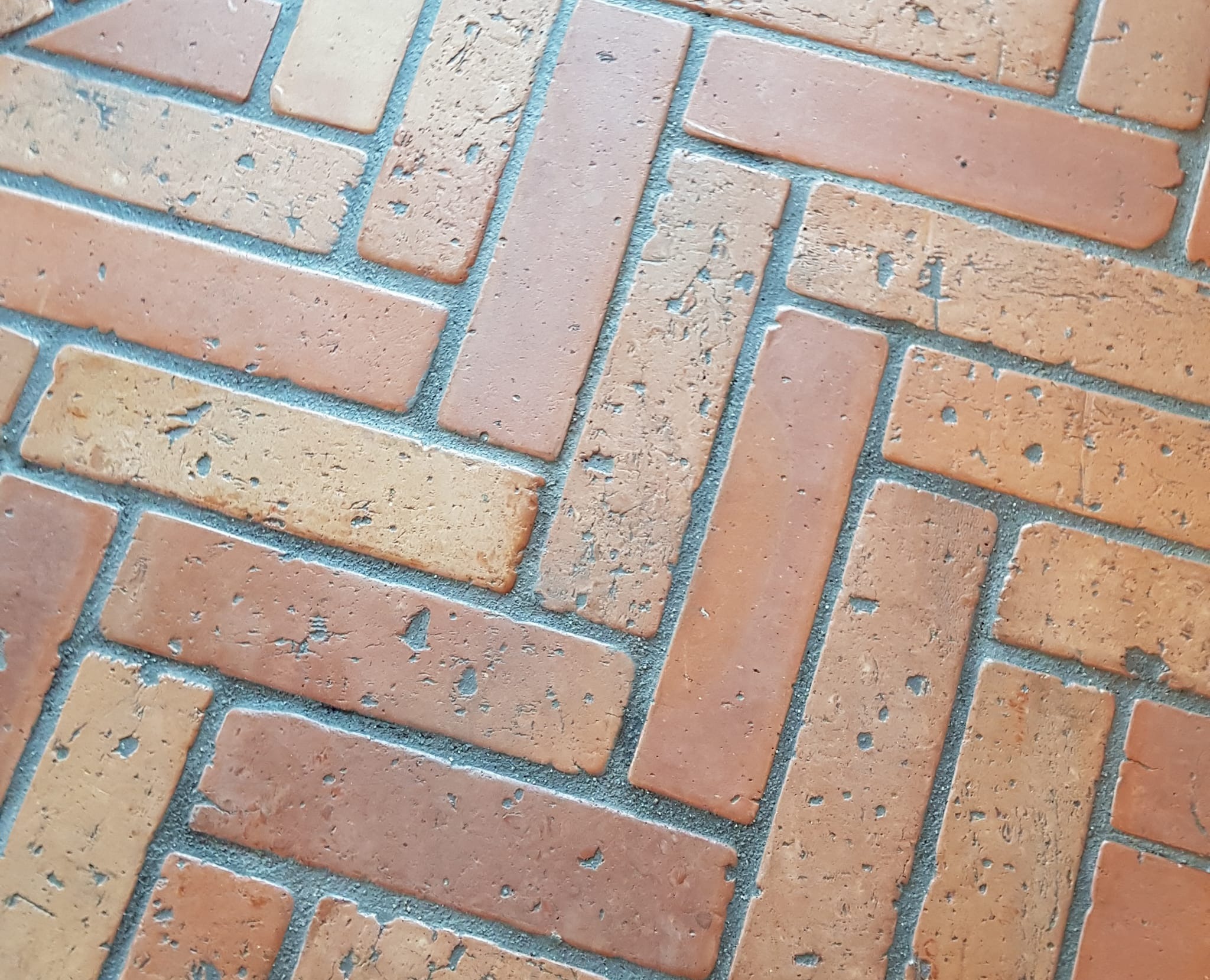 Ułożona cegła klinkierowa w jodełkę, tworząca podłogę w stylu loftowym. Detal wykończenia w Szczytnie. Widoczne nierówności i porowatość cegieł.