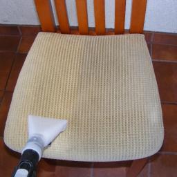 TobiRobi - Czyszczenie beżowego krzesła tapicerowanego z widoczną końcówką odkurzacza piorącego i brązową podłogą z płytek w tle.