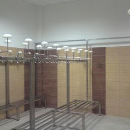 FRENO Spółka z ograniczoną odpowiedzialnością - Szare metalowe szafki i ławki w szatni wyłożonej brązowo-beżowymi płytkami, oświetlenie punktowe w kształcie grzybków.