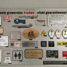 Ekspozycja grawerowanych laminatów i tabliczek informacyjnych, w tym logo firm, oznaczeń WiFi, tabliczek z nazwiskami, oznaczeń toalet, instrukcji i nagród, wykonanych na laserach Trotec Speedy.