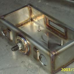 FRENO Spółka z ograniczoną odpowiedzialnością - Spawana metalowa obudowa z otworami i gwintowanym trzpieniem, widoczne ślady spawania i data 2003/12/02