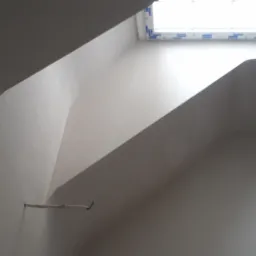 Poddasze z oknem dachowym po nałożeniu gładzi, widoczny fragment instalacji elektrycznej i rurka wystająca ze ściany.