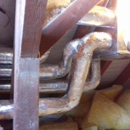 Hydro-Team - Srebrne, izolowane rury wentylacyjne poprowadzone pod drewnianym stropem, widoczna wełna mineralna.