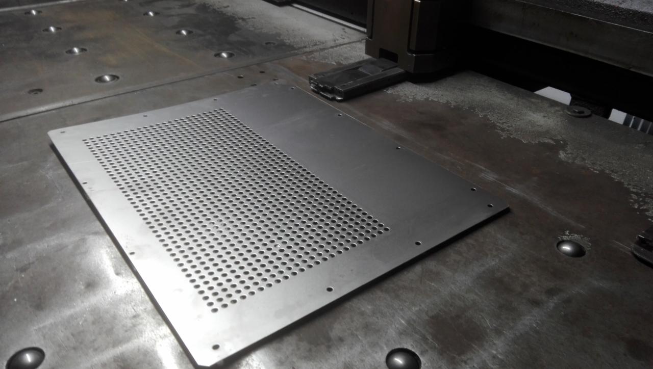 Proces wykrawania perforacji na metalowej płycie w Warka, widoczna maszyna CNC i obrabiany element.