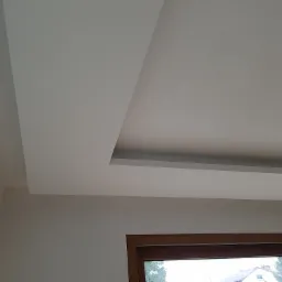 Sufit podwieszany z płyt karton gips w Chynowie, z widocznym fragmentem okna z drewnianą ramą, oświetlony światłem dziennym.