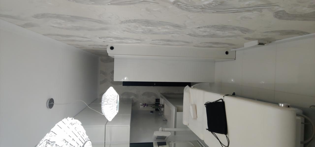 Nowoczesna łazienka z białymi meblami, ozdobnym sufitem i designerskimi lampami wiszącymi.