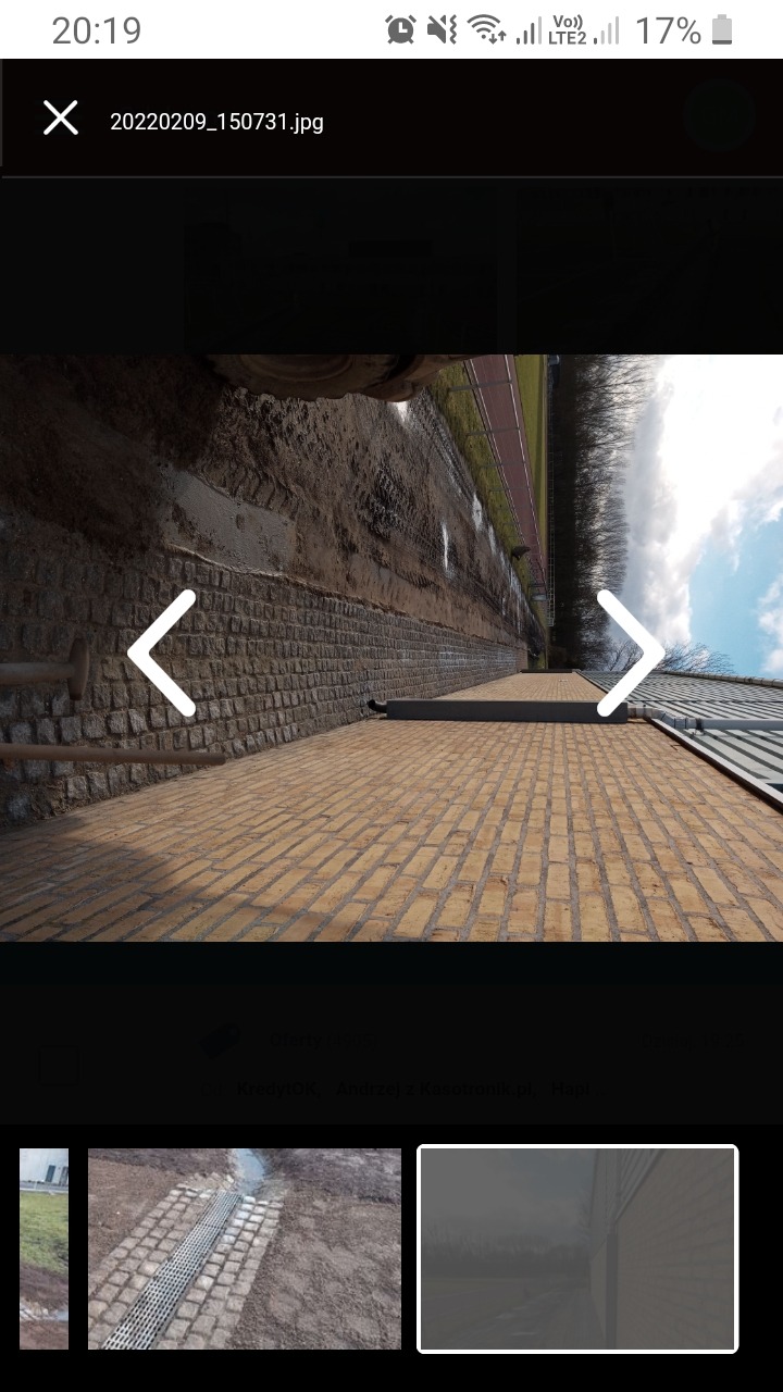 Żółta kostka brukowa ułożona na ścieżce obok kamiennego muru i bieżni lekkoatletycznej, widok z perspektywy żaby.