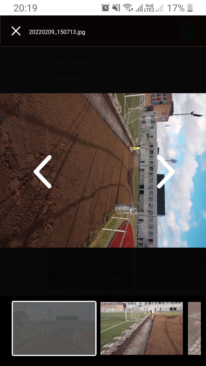 Prace ziemne przygotowawcze pod budowę nawierzchni na stadionie, widoczny pracownik w odblaskowej kamizelce i budynek w tle.