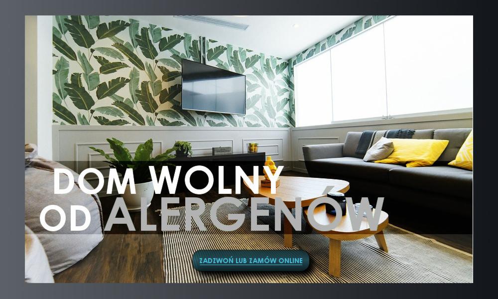 Nowoczesny salon z tapetą w liście, szarą sofą z żółtymi poduszkami i drewnianym stolikiem kawowym, z hasłem 'Dom wolny od alergenów' na pierwszym planie.