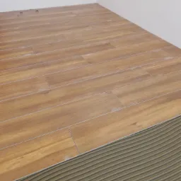 Układanie drewnopodobnych płytek podłogowych w Szklanej, widoczna warstwa kleju z charakterystycznymi rowkami i fragment białej ściany.