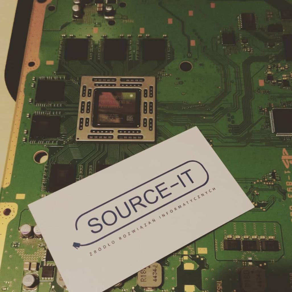 Płyta główna komputera z procesorem i wizytówką firmy SOURCE-IT, specjalizującej się w rozwiązaniach informatycznych.