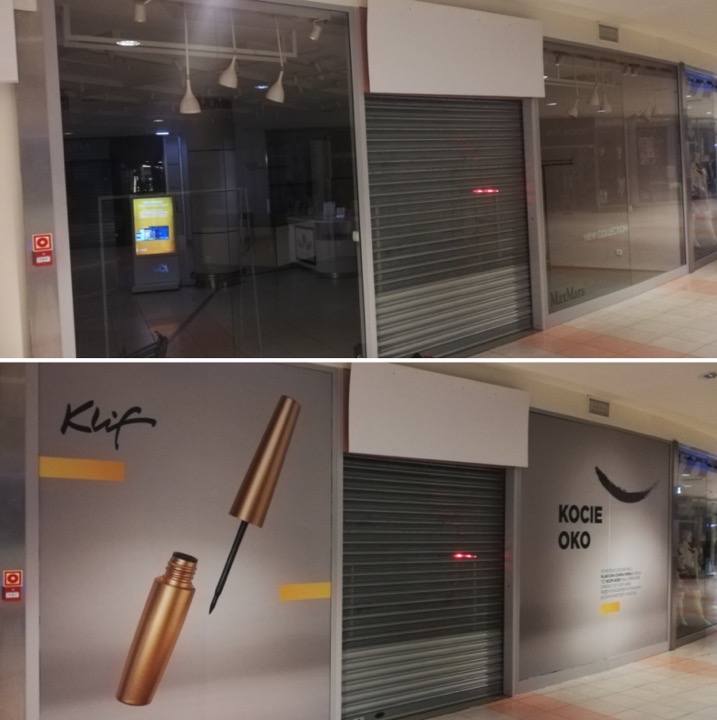 Zasłonięte rolety sklepowe w galerii handlowej, oklejone reklamami kosmetyków do makijażu oczu.