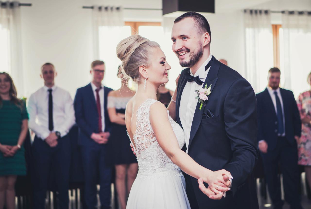 Para młoda tańczy podczas wesela, w tle goście weselni.