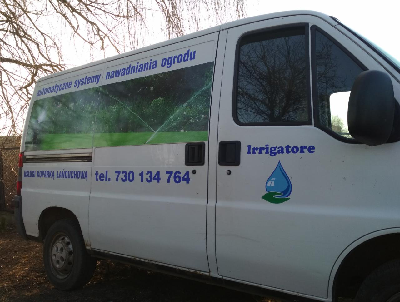 Biały samochód dostawczy z reklamą automatycznych systemów nawadniania ogrodu, logo firmy 'Irrigatore' z kroplą wody i numerem telefonu