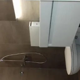 Nowoczesna łazienka z beżowymi płytkami, podwieszaną toaletą z białą zabudową i chromowaną baterią prysznicową