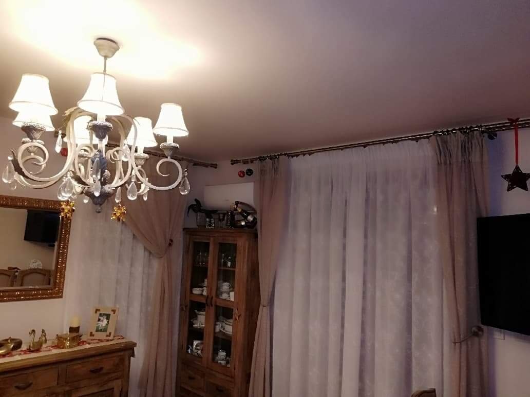 Wnętrze salonu w Rzeszowie z widoczną jednostką klimatyzacji zamontowaną nad drewnianą witryną, zasłoniętą częściowo przez firanki.