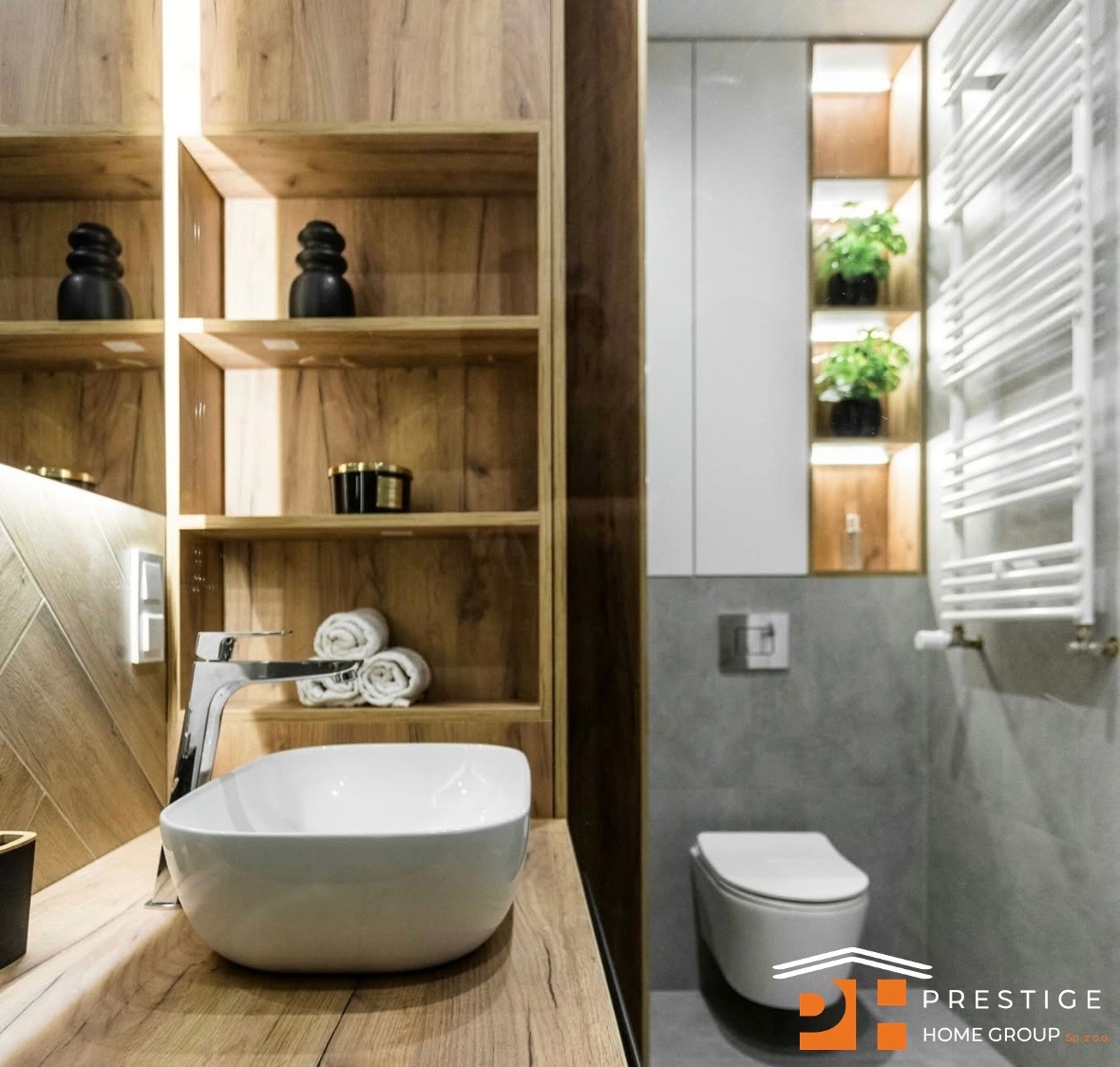 Nowoczesna łazienka z drewnianymi półkami, białą umywalką i grzejnikiem drabinkowym. Uwagę przykuwają rośliny w podświetlanych niszach i armatura.