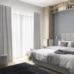 Blanka Mróz - Nowoczesna sypialnia w odcieniach szarości z dekoracyjną lampą sufitową, teksturowaną ścianą i roślinną dekoracją w rogu, oświetlona naturalnym światłem z okna.