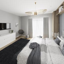 Blanka Mróz - Nowoczesna sypialnia w odcieniach szarości z łóżkiem z pikowanym zagłówkiem, designerską lampą sufitową i czarnym dywanem.