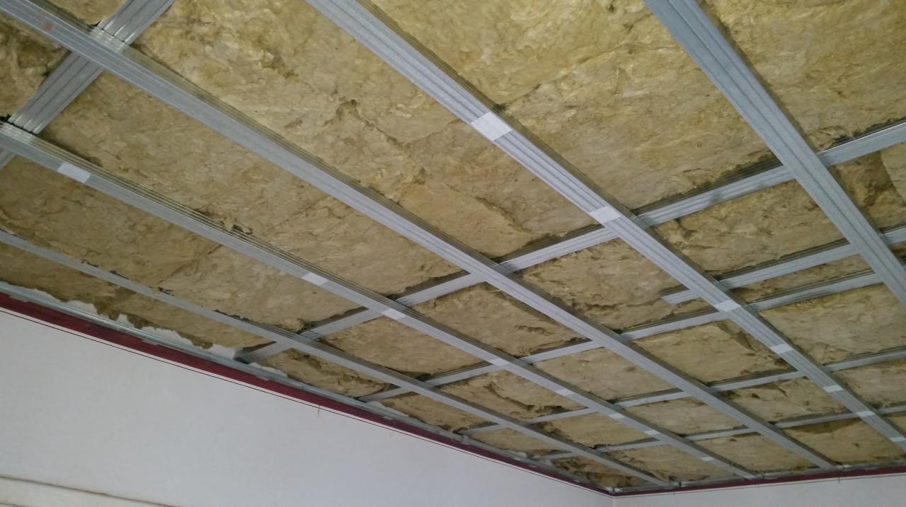Montaż sufitu napinanego: widoczne metalowe profile konstrukcyjne i izolacja z wełny mineralnej przed nałożeniem membrany.