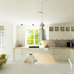 Jasna kuchnia w stylu klasycznym z wyspą i srebrną lampą wiszącą, widok na okno z zielenią na zewnątrz, na pierwszym planie kosz z zielonymi jabłkami.