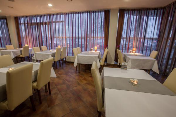 Elegancko przygotowana sala restauracyjna w Warszawie z nakrytymi stołami, świecami i zasłonami w odcieniach brązu i fioletu.