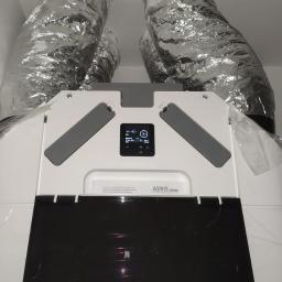 SOLTHERM Włodzimierz Pastuszak - Centrala wentylacyjna z rekuperacją AERIS, widoczne srebrne rury wentylacyjne i panel sterowania z wyświetlaczem.