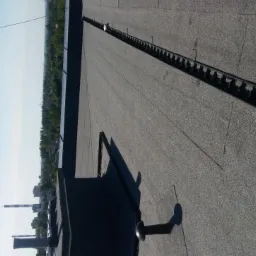 Wykończony, płaski dach pokryty papą termozgrzewalną z zamontowanym systemem odgromowym i elementami wentylacji, widok z góry na tle zieleni i zabudowań miejskich.