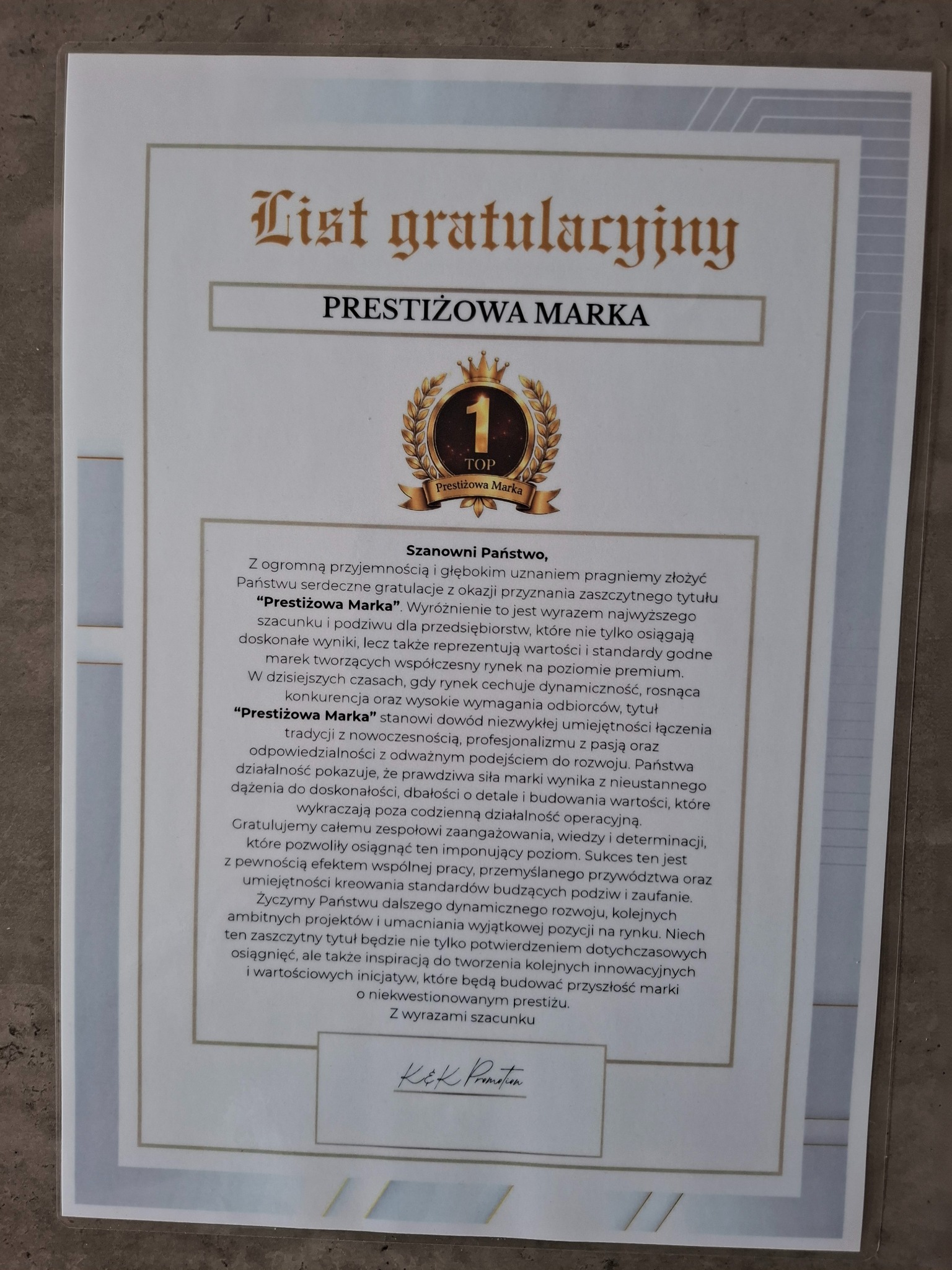 Uznanie 'Prestiżowa Marka': List gratulacyjny z tekstem, logo i podpisem, potwierdzający wysoką pozycję na rynku i innowacyjność firmy. Dokument w ramce.