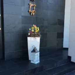 Eleganckie wejście do domu z ciemną okładziną ścienną, dekoracją świąteczną i lampionem.